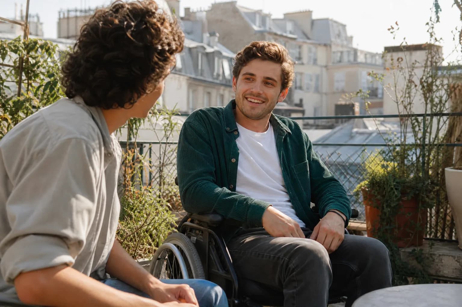 Un jeune homme en fauteuil roulant discute avec un ami en terrasse