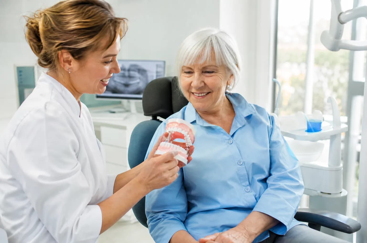 Une chirurgienne-dentiste montre un modèle dentaire à sa patiente